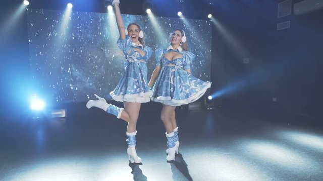 Beautiful cheerful girls in Christmas costumes perform on a stage. Dance show.