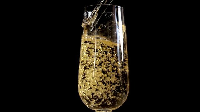 Champagne is poured into a glass in Slow Motion on a black background 