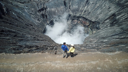 Traveler lover couple holding hand with fume of volcano background at Mt.Bromo (Gunung Bromo) Kingkong hill East Java, Indonesia