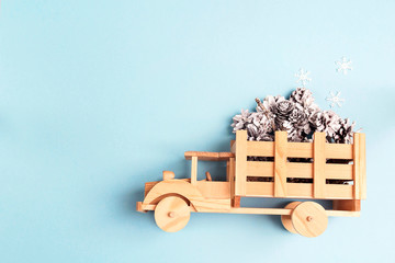 Winter holiday toy truck with snow painted pine cones on blue background.