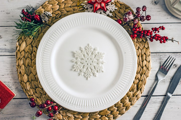 Christmas table setting - plate, cutlery and christmas decorations on light wooden table. Top view.