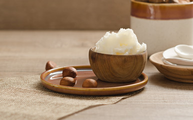 Shea butter and nuts on a wooden board, copy space.