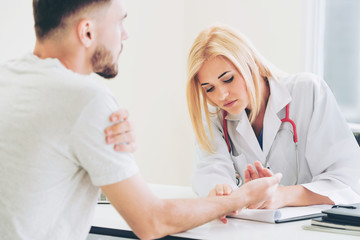Woman doctor is talking and examining male patient in hospital office. Healthcare and medical...