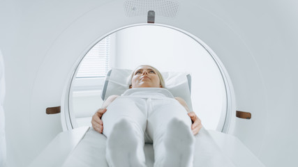 Close-up Portrait Shot of a Female Patient Lying on a CT or MRI Scan, Bed is Moving Inside the...