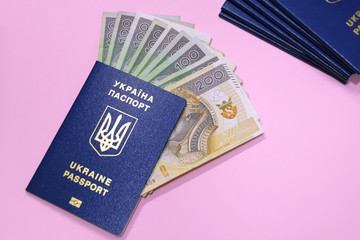 Ukraine passports with golden letters and trident emblem on violet blurred background. Stack of id documents with poland currency polish zloty. Ukrainiant migrant wokers documents.