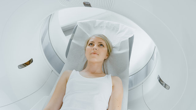 In Medical Laboratory Male Radiologist Controls MRI Or CT Or PET Scan With Female Patient Undergoing Procedure. High-Tech Modern Medical Equipment.