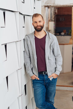 Casual man leaning on wall and smiling at camera