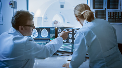 In Control Room Doctor and Radiologist Discuss Diagnosis while Watching Procedure and Monitors...