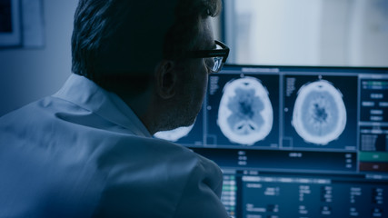 In Medical Laboratory Patient Undergoes MRI or CT Scan Process under Supervision of Radiologist in Control Room, He Watches Procedure and Monitors Brain Activity Results.