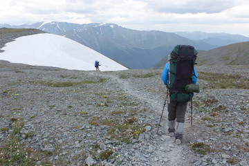 Tourist man coming down from the  snow slope of the Pass Kara-Turek, Altai Mountain, Russia