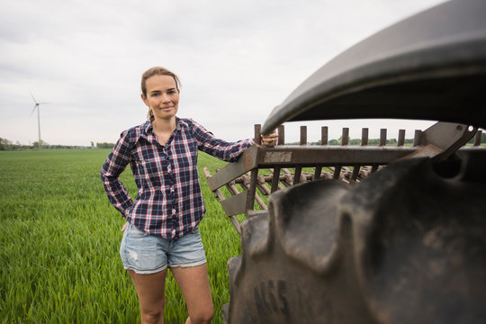 Agricultural worker standing next to a tractor in field