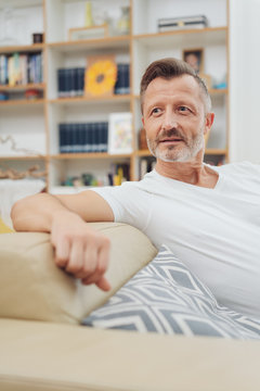 Man relaxing on a sofa watching something behind