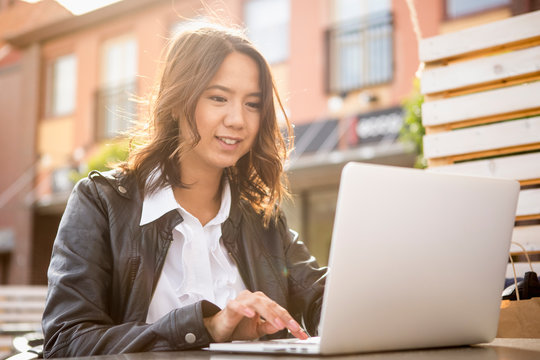 Smiling young woman using laptop outdoors