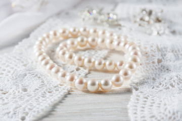 White pearl necklace on handmade lace background.
