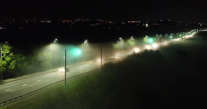 Dangerous road traffic on country highway on foggy night, aerial shot