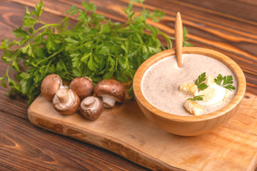 Tasty pureed mushroom soup in wooden bowl with ingredients