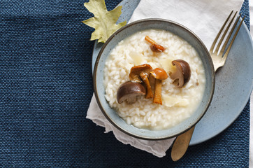 Risotto with mushrooms and parmesan cheese in blue plate on rustic linen tablecloth. Copyspace.