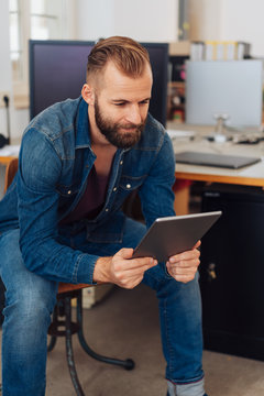 Stylish, modern man looking at tablet in office