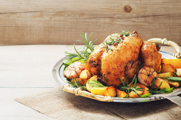 Festive roast chicken with potatoes,garlic and rosemary on wooden rustic table.