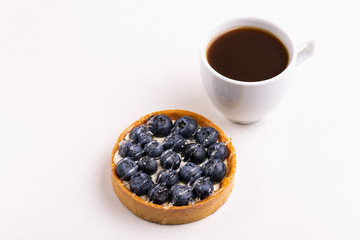 Tasty blueberry tart with vanilla cream and cup of coffee
