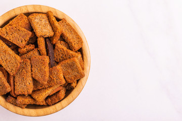 Rye salted crackers in wooden bowl on light marble background