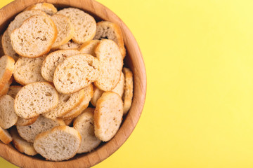 Wheat salted crackers in wooden bowl on bright colored background