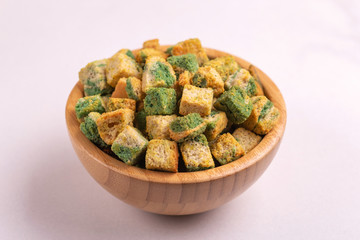 Spinach flavored crackers in wooden bowl on light marble background