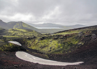 Green moss-covered volcanic mountains and blac lava field. Landmannalaugar. Iceland