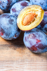 Ripe plums scattered on wooden background.