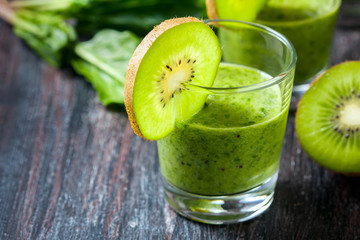 Healthy green smoothie from spinach and kiwi on a wooden table