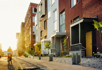 Adult bicycling by townhouses at sunset in Helsinki, Finland