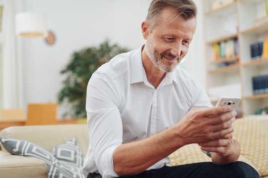 Middle-aged man smiling as he reads an sms