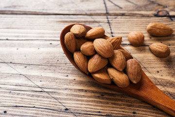 Almonds in wooden spoon on wooden background. Copy space.