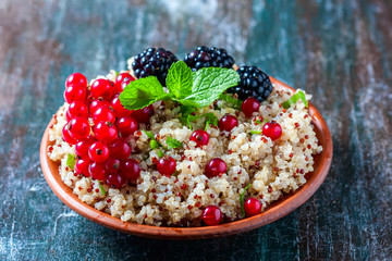 Quinoa salad with berries, mint and walnuts on a dark wooden background. Superfoods  clean eating concept.