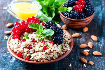 Quinoa salad with berries, mint and walnuts on a dark wooden background. Superfoods  clean eating concept.
