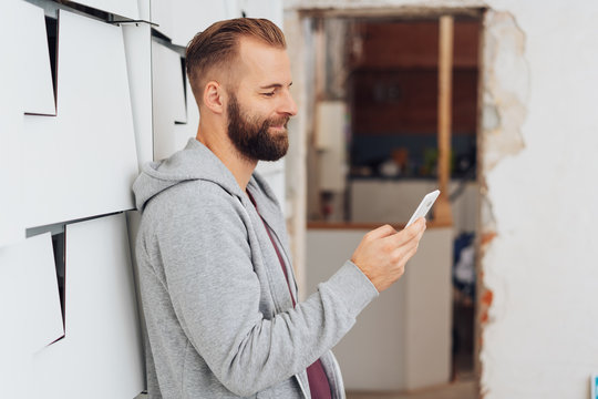 Casual man at home smiling while texting on phone
