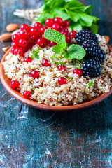 Quinoa salad with berries, mint and walnuts on a dark wooden background. Superfoods  clean eating concept.