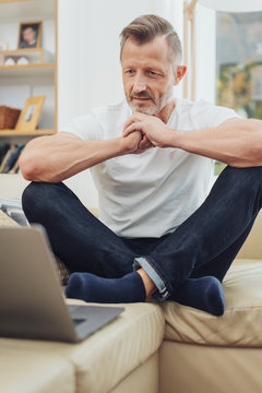 Middle-aged man sitting cross legged on a sofa