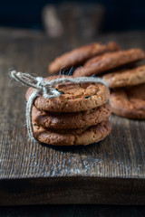 Oatmeal cookies with raisins, chocolate folded in a pile on the old table, wood background