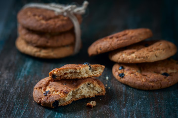 Oatmeal cookies with raisins, chocolate folded in a pile on the old table, wood background