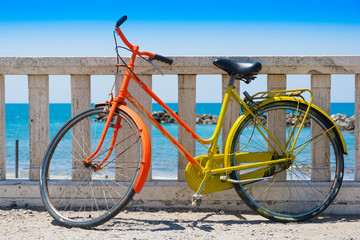 Fototapeta na wymiar Bicicletta vintage colorata di rosso e giallo in riva al mare in estate
