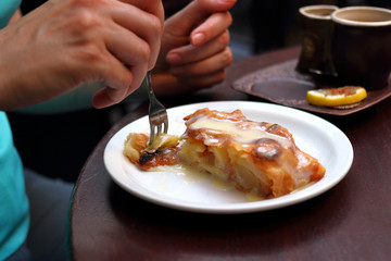 Woman eating delicious strudel dessert at restaurant. Hand with fork