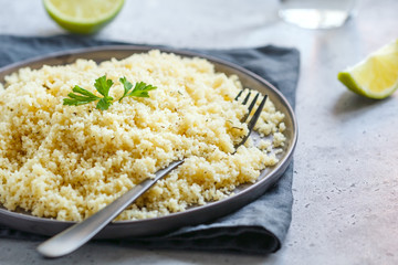 Couscous on a black ceramic plate on a table. The concept of vegetarian and healthy food.