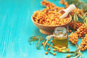 Natural, organic sea-buckthorn berry in bowl and and sea buckthorn oil in glass vintage bottle