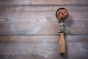 Scoop of chocolate ice cream on rustic wooden background.