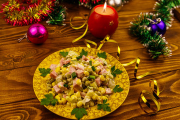 Fototapeta na wymiar Tasty festive salad, Christmas decor and candle on wooden table