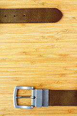 Leather belt hinges on wooden background with copy space 