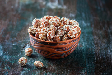 Sugared peanuts with sesame seeds on the wooden background
