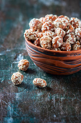 Sugared peanuts with sesame seeds on the wooden background