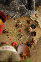 Details of still life in the living room home interior. Beautiful cup of tea with spices and sweaters on a wooden background. Cozy autumn-winter concept.